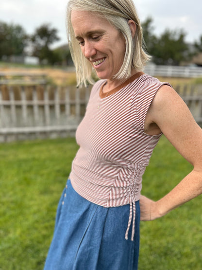 Woman wearing a pink sleeveless top and blue pants outdoors.

